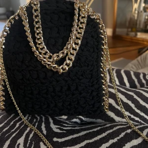 Svart stickad axelväska med guldkedja - Intressekoll på  en superfin svart stickad axelväska med en snygg guldkedja som axelrem. 