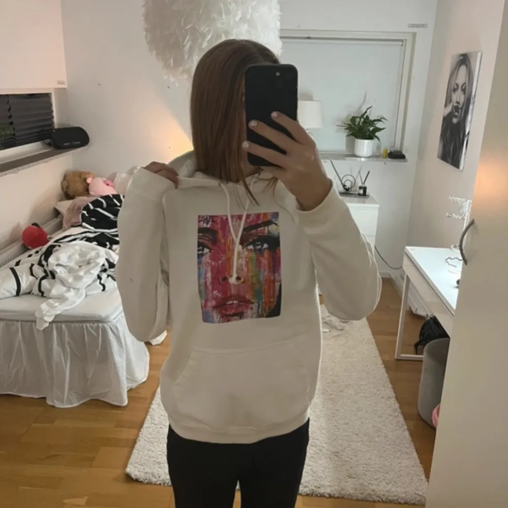 Säljer en superfin vit hoodie med ett stort färgglatt ansikte tryckt på framsidan. Den är i bra skick och perfekt för både höst och vår. Hoodien har en normal passform och är gjord i mjukt material, vilket gör den riktigt bekväm att ha på sig. Perfekt för chill dagar eller när du vill ha något snyggt och bekvämt! 💖. Tröjor & Koftor.