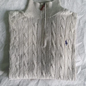 Vit stickad Ralph lauren Halfzip!! - Hej!! Säljer en jätte snygg och super stilig Ralph lauren halfzip. Den är en blandning mellan vit och beige i färg och är I storlek S som syns på lappen på bilderna. Den är i bra skick och har inga hål eller defekter! Dessutom så är den varm och super mysig som gör den perfekt för dom kommande kalla månaderna!! Priset är redan prutat men det går att förhandla. Skriv såklart om ni har fler frågor eller funderingar!!:)