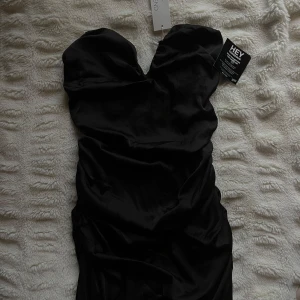 Svart bandeau klänning - Snygg svart axelbandslös klänning i satin. Perfekt för festliga tillfällen och speciellt nyår!! Prislapp kvar