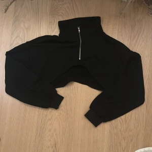 Svart croppad dragkedja - Säljer en svart croppad hoodie med dragkedja. Den har en hög krage och långa ärmar med ribbade muddar. Perfekt för emo och alt 💫
