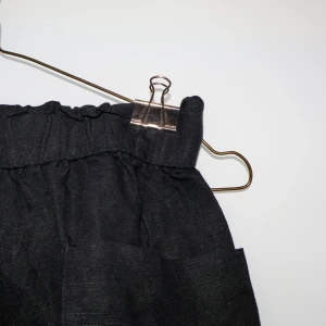 Svarta linneshorts från H&M - Säljer ett par svarta linne-shorts från H&M i storlek 38. De är högmidjade med en elastisk midja för extra komfort. Perfekta för sommardagar. Shortsen är i bra skick och redo för nya äventyr!