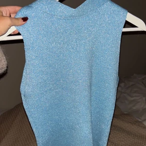 Glittrig blå ärmlös topp - Säljer en superfin glittrig blå ärmlös topp. Perfekt för festliga tillfällen! Toppen är i mycket bra skick.