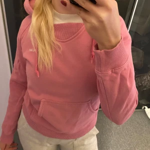 Rosa hoodie från Reebok - Säljer en snygg rosa hoodie från Reebok i bra skick. Den har en klassisk känguruficka och justerbar huva med dragsko. Perfekt för en avslappnad stil eller träning. Superbekväm och mjuk!