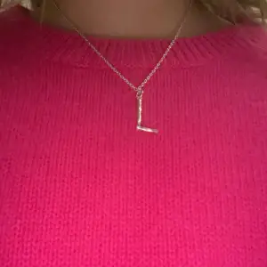 Snyggt och stilrent silverhalsband med ett hänge i form av bokstaven 'L'. Perfekt för att ge en personlig touch till din outfit. Kedjan är tunn och elegant, vilket gör den lätt att bära till både vardags och fest. Ett måste för alla som älskar minimalistiska smycken!Är från Maria Nilsdotter och kostar igentligen 1900