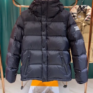 Svart dunjacka från Burberry - Säljer en snygg svart dunjacka från Burberry. Den har en klassisk pufferstil med en huva och dragkedja. Jackan är perfekt för kalla vinterdagar och har en stilren design med Burberry-logga på ärmen. Insidan har det ikoniska rutiga mönstret. Passar perfekt för både vardag och fest!