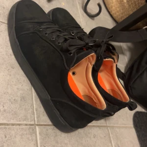 Christian Louboutin - Säljer ett par snygga svarta sneakers i mocka med coola röda sulor. De har snörning och en stilren design som passar perfekt till vardags eller fest. Skorna är i bra skick. Använder comfort sulor för har problem med hälen men säljs med original sula. Allt og tillkommer. Pris kan diskuteras