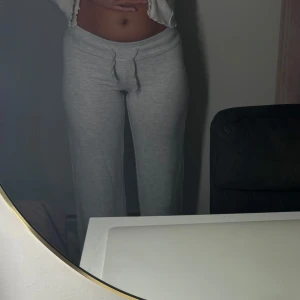 Gina tricot mjukisbyxor  - Superbekväma grå mjukisbyxor i normal passform. Perfekta för mysiga dagar hemma eller en avslappnad dag ute. De har en praktisk snörning i midjan för justerbar passform. Materialet är mjukt och skönt, vilket gör dem till ett måste i garderoben.