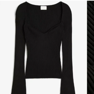 Svart ribbad topp - Snygg svart ribbad topp med långärmad design och en djup v-ringning. Den är gjord i ett mjukt och stretchigt material.