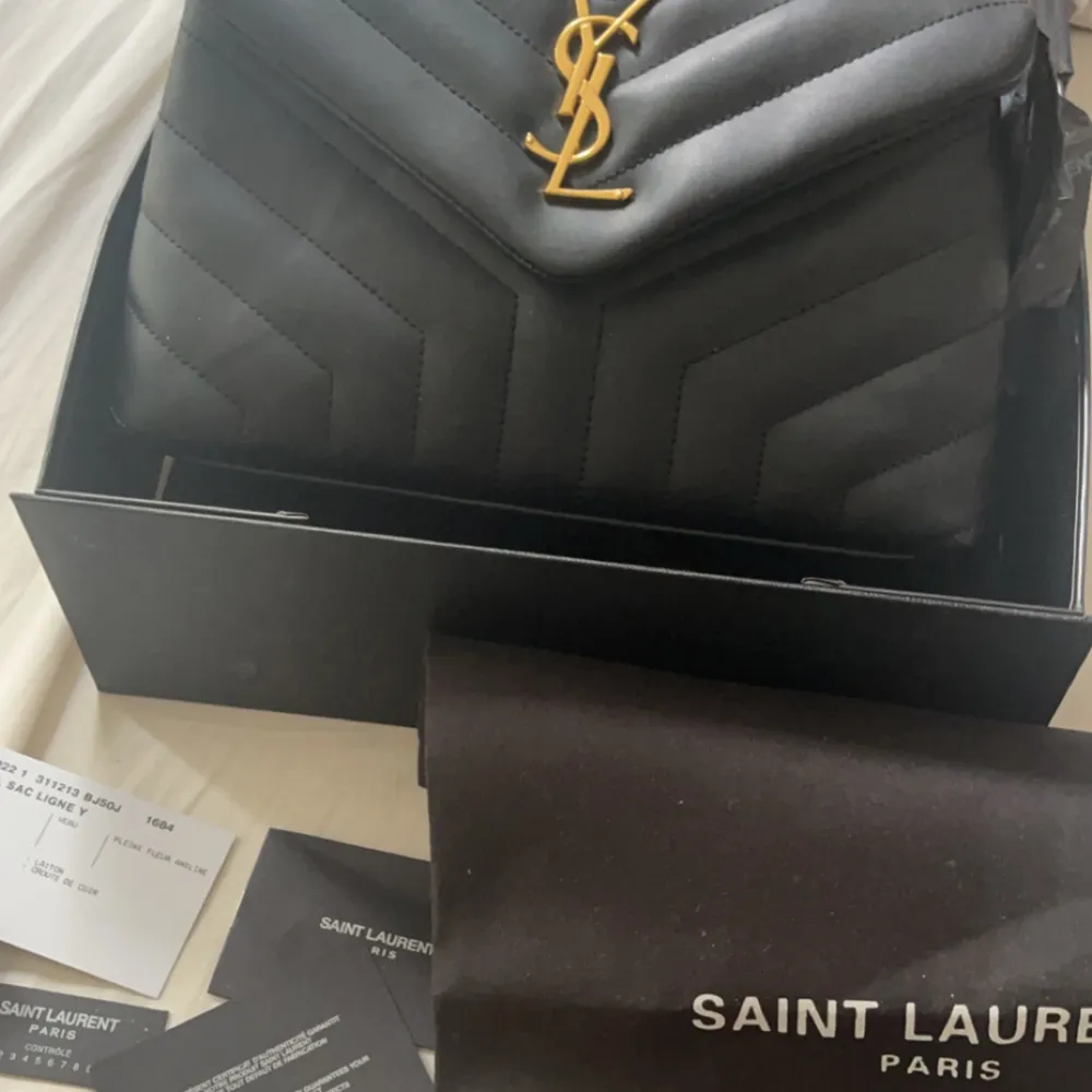 Säljer en elegant svart axelväska från Saint Laurent i skinn. Väskan är knappt använd och är i väldigt bra skick! Kommer med dustbags, certifikat och låda! 🫶🏼. Väskor.