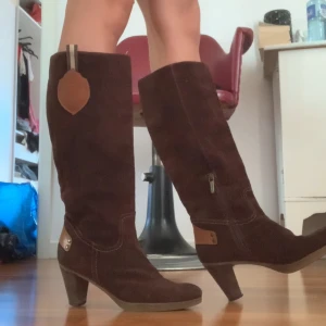  mockastövlar med klack - Säljer ett par snygga bruna stövlar i mocka med klack, storlek 38. De har en dragkedja på sidan och dekorativa detaljer i läder. Perfekta för höst och vinter. De har lite skavanker på klacken som syns om man tittar på nära håll, men annars perfekt kvalitet och superbekvöma! ❤️