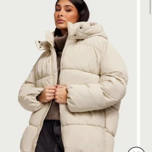 Beige pufferjacka - Säljer en supermysig beige ”pufferjacka” som är perfekt för kalla dagar. Jackan har en hög krage och dragkedja framtill. Perfekt för vintern. Köpt förra vintern men inte använd nått kanske en gång, sen har den bara hängt i garderoben så den är som ny! Nypris 699kr🫶🏼