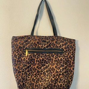 Leopardmönstrad väska från Victoria Secret  - Säljer en leopardmönstrad shoppingväska från Victoria Secret i nyskick. Väskan har en praktisk dragkedja och svarta handtag. En ficka med dragkedja inuti samt 2 mindre fickor. Inga defekter🐆✨
