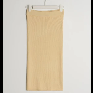 Beige ribbad kjol - Säljer en superfin beige ribbad kjol som är perfekt för både vardag och fest. Kjolen är lång och har en tight passform som framhäver figuren. Den är gjord i ett mjukt och stretchigt material som gör den bekväm att bära hela dagen. Perfekt att matcha med en oversized tröja eller en snygg blus!