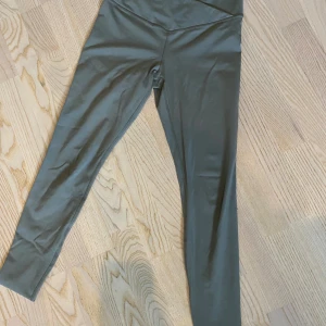 Gröna leggings i polyester och elastan - Säljer ett par gröna leggings i storlek S. De är tillverkade av 79% polyester och 21% elastan, vilket gör dem superstretchiga och bekväma. Perfekta för träning eller en avslappnad dag hemma. De har en enkel design utan mönster och är i nyskick.