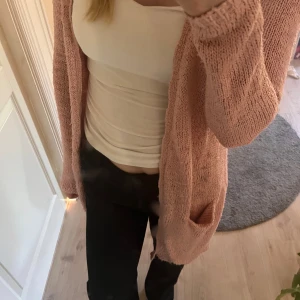 Rosa stickad kofta - Säljer en supermysig rosa stickad kofta. Perfekt för kyliga dagar när du vill ha något bekvämt och stilrent. Koftan har långa ärmar och en lös passform som gör den lätt att matcha med olika outfits. Den är i bra skick och redo för en ny ägare!