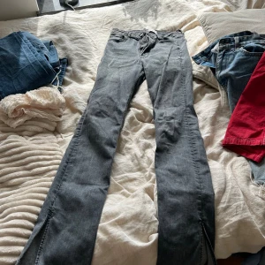 Grå jeans från Zara - Säljer ett par grå jeans från Zara i storlek 38. De är i bra skick och har en snygg, klassisk design med dragkedja och knapp. Perfekta för både vardag och fest!