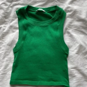 Grönt linne från Zara - Croppat grönt linne från Zara. Tjockare och töjbart tyg med god kvalitet! Perfekt till sommar eller under en kofta för att få färg på en outfit!! Använt endast en gång. 