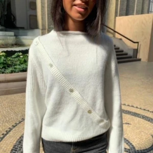 Vit stickad tröja med knappar - Säljer en superfin vit stickad tröja med en unik design. Den har långa ärmar och en snygg detalj med knappar. Perfekt för både höst och vinter.Passar till både jeans och kjol! Jag kommer inte ihåg vad jag köpte den för och är därför redo att  diskuterar priset 