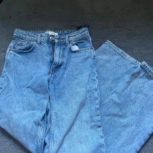 Blå jeans från Zara - Säljer ett par snygga blå jeans från Zara i modellen 'The Midwaist Straight'. De är i storlek XS och har en klassisk straight passform. Perfekta för både vardag och fest!