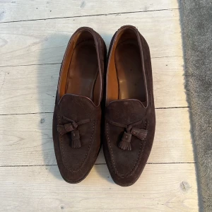 Bruna mocka loafers med tofsar - Säljer ett par bruna mocka loafers från Meermin. Storlek 42,5. Sula är trä.