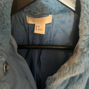Blå pälsjacka - Säljer en supermjuk och fluffig blå pälsjacka i storlek S. Den har en klassisk krage och två fickor med dragkedjor framtill. Perfekt för att hålla sig varm och stilren under kyliga dagar. Jackan är i bra skick och redo för en ny ägare!