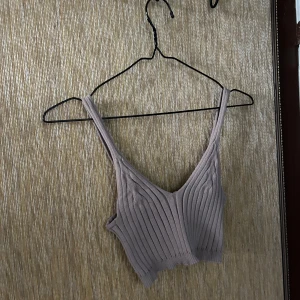 Beige ribbad linnetopp - Säljer en superfin beige ribbad linnetopp. Den är ärmlös och har en snygg v-ringad design. Perfekt för sommardagar eller som ett lager under en jacka. Toppen är i ett mjukt och stretchigt material som sitter skönt på kroppen.