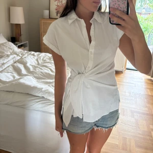 Vit skjorta från Zara storlek M - Vit kortärmad skjorta från Zara i storlek M med knyte i midjan. Använd endast 1 gång tyvärr. Köpt för 400kr.