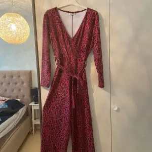 Snygg röd jumpsuit med leopard mönster från Nakd. Prislapp sitter kvar helt oanvänd. Storlek 36