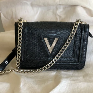 Valentino axelrems väska  - Svart med ormskinns mönster präglat  Klassiska V i lite annorlunda variant  Inte Valentino budget variant utan deras riktiga line  Bra storlek och rymmer de du behöver  Använd men i fint begagnat skick  Mario Garavani  Svart med Silver detaljer 