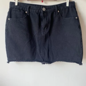 Svart jeanskjol från Boohoo - Säljer en snygg svart jeanskjol från Boohoo. Kjolen har en klassisk femficksdesign och en rå kant nertill för en cool look. Perfekt för både vardag och fest! 🖤