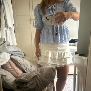 Vit jeanskjol m. volanger - Snygg vit jeanskjol med volanger från Gina Tricot som tyvärr inte kommit till användning! Storleken är 40 men passar mig som brukar bära strl 38 i jeans.