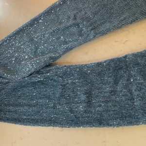 Blå glittriga byxor från Stine Goya - Säljer ett par supercoola blå byxor från Stine Goya. De är täckta med glittriga paljetter som verkligen får dem att sticka ut. Perfekta för en fest eller en kväll ute när du vill glänsa lite extra. Byxorna är i storlek XS och har en bekväm passform.