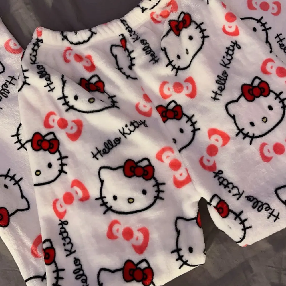 Supermysiga populära vita mjukisbyxor med Hello Kitty-motiv över hela tyget. Byxorna har ett gulligt mönster med röda rosetter och Hello Kittys ansikte. Perfekta för en chill dag hemma eller som pyjamasbyxor. De är gjorda i ett mjukt och bekvämt material som känns skönt mot huden. 💕💕 . Jeans & Byxor.