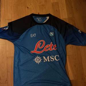 En riktigt snygg EA7 Napoli Fotbollströja i storlek L, med skönt material endast använd ett par gångee i gott skick!