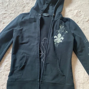 Bcbg tröja - Svart bcbg tröja med tryck på ryggen och armen. Vet it om den hade snöre i början men skulle kunna tror det men dom finns inte kvar! Bra skick. Köpare står för frakt! Tvättar innan jag skickar! 