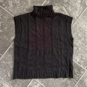 Svart stickad ärmlös polotröja - Säljer en svart stickad polotröja som är ärmlös och perfekt för lager-på-lager-stil. Den har ett snyggt mönster och en hög krage som håller dig varm. Passar både till vardags och lite finare tillfällen. Superbekväm och lätt att matcha med andra plagg! Passar både S och M.