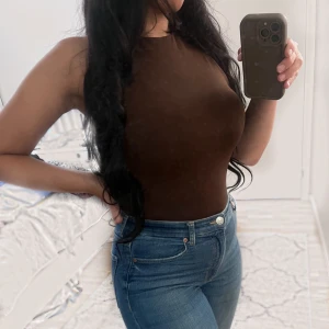 2 st Zara body i brun och svart  - Snygg body från Zara i storlek S i två olika färger, brun och svart.  Bodyn har en hög hals och är figursydd.  Perfekt för att skapa en elegant look. Crewneck med hög hals och utan ärmar. Brun body, ärmlös body, hög hals, crewneck body, Zara body, st