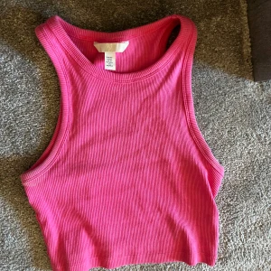 Rosa ribbad linnetopp - Säljer en superfin rosa ribbad linnetopp i storlek XS. Perfekt för sommardagar eller som ett lager under en jacka. Toppen är ärmlös och har en tight passform som framhäver figuren. Ett måste i garderoben för en färgglad touch!