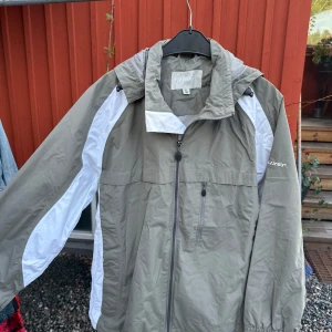 Beige och vit vindjacka från Tuxer - Säljer en beige och vit vindjacka från Tuxer i storlek XL. Jackan har en dragkedja framtill och är långärmad. Perfekt för höst och vår.