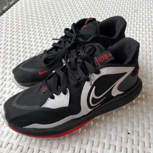 Svarta och röda Nike sneakers - Ett bra par basketskor(kyrie 5 low) i färg röd svart och vit. Använt ca 4 gånger. Normalt pris 1100kr säljs för 500kr. Riktigt bra om man kör basket. Kan också användas som idrottsskor.