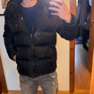 Ralph Lauren Jacka - Skit snygg Polo Ralph Lauren jacka i svart! Jag på bilden är 178. Jackan har några små defekter som visas på bilderna men inget man märker vid användning.  Jackan är XL i barnstorlek men sitter som herr storlek Xs/s. Om du har några frågor är det bara att skriva! 