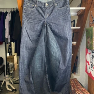 Baggy Low Waist Jeans - Säljer mina handgjorda mörkblåa baggy flared jeans med riktig snygga bakfickor som har både studs och glittriga sömmar. Storlek 32/32 eller 42,5cm i midjan, 104cm långa och 36cm i benöppningen. Skriv gärna om du undrar något!