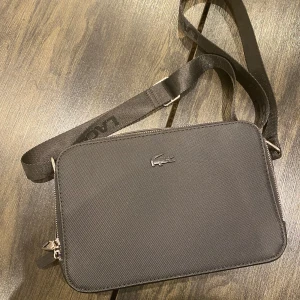 Lacoste Messenger Bag - Säljer en Lacoste Messenger bag som är perfekt för att lägga sina grejer i och samtidigt vara stilig !   Priset är ej hugget i sten !
