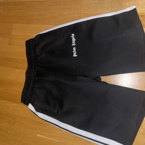 Svarta shorts med vit rand från Palm Angels - Snygga svarta shorts från Palm Angels med vita ränder längs sidorna. Perfekta för en avslappnad stil. Elastisk midja för bekväm passform.