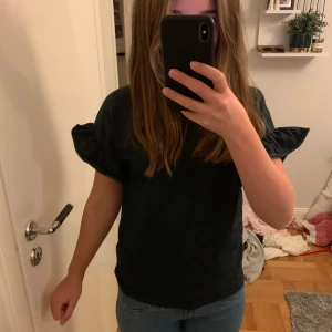 Svart glittrig topp - Svart glittrig topp med korta puffärmar. Storlek 134-140 men är större i verkligheten.