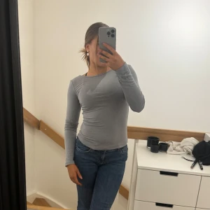 Grå långärmad topp - Snygg och enkel grå långärmad topp med tight passform. Perfekt för en stilren vardagslook. Passar bra till jeans eller kjol.