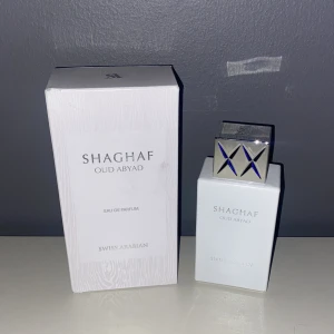 Shaghaf Oud Abyad Eau de Parfum - KOM GÄRNA MED BYTESFÖRSLAG! Shaghaf Oud Abyad från Swiss Arabian är en elegant Eau de Parfum med en stilren vit flaska och en dekorativ silverfärgad kork med blå detaljer. Doften är känd för sina rika och exotiska noter av oud, vilket ger en lyxig och långvarig upplevelse. Perfekt till speciala tillfällen eller bara använda dagligen. 74ml kvar av 75 som syns på bilden. Lik Amouage Interlude.