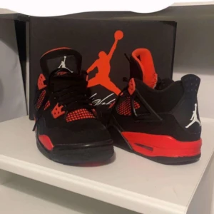 Air Jordan 4 Retro GS - Snygga Air Jordan 4 Retro GS i svart och röd färgkombination. Skorna har en ikonisk design med snörning och Jumpman-logga. Perfekta för sneaker-entusiaster som vill ha en klassisk stil. Kvittot finns att visa privat om det behövs 