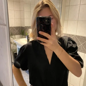 Svart topp med puffärmar - Snygg svart topp med puffärmar och v-ringning 